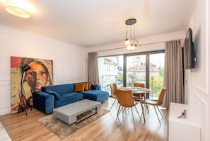 Una sala de estar moderna con un sofá azul, una mesa de centro y un comedor con mesa y sillas.