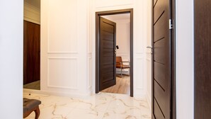 A hallway with a marble floor, a wooden bench, and a door leading to another room.