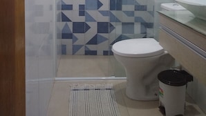 Ein Badezimmer mit einem geometrischen Fliesenmuster, einer Toilette, einem Waschbecken und einer Duschkabine.