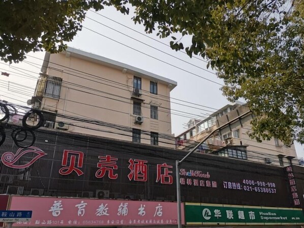 Un albergo con segnaletica che indica 'Beijing Hotel' e 'Hualian Supermarket'.