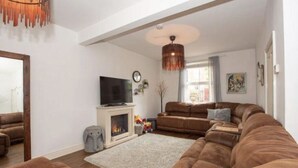 A living room with a fireplace, sofas, a television, and a large window.