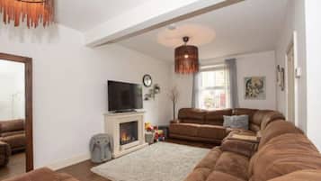A living room with a fireplace, sofas, a television, and a large window.
