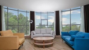 A modern living room with a round coffee table, two sofas, and large windows offering a view of greenery. - City Comfort Inn Yuzhou Dayuxiang (Xuchang)