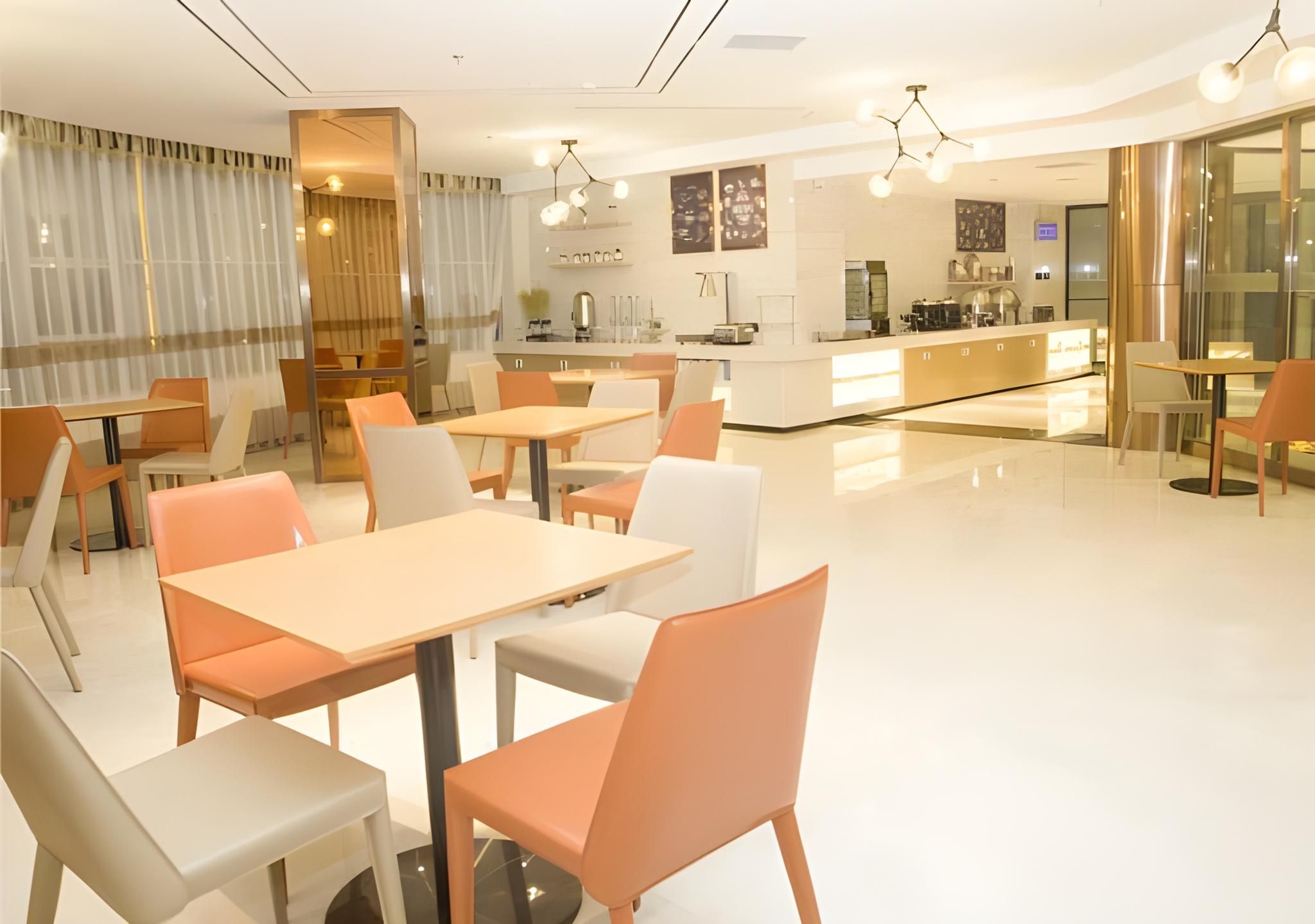 A modern restaurant with a bar area, tables, and chairs.
