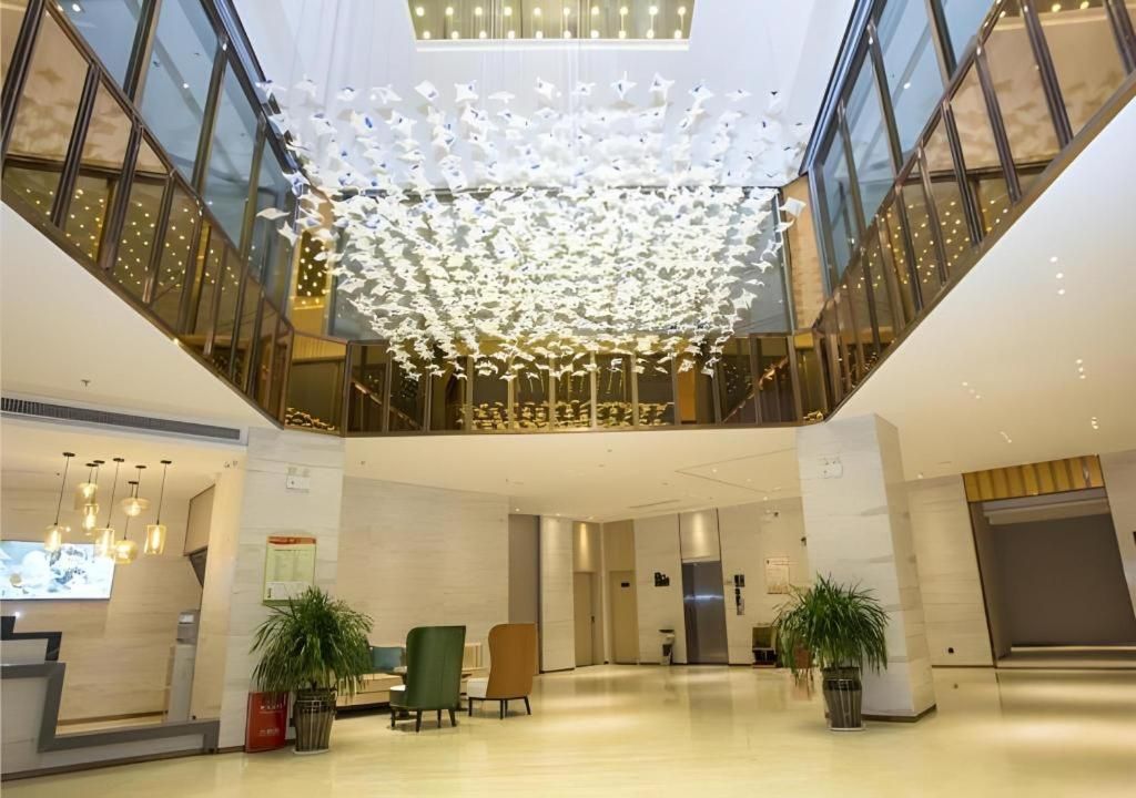 Eine großzügige Lobby mit hoher Decke, moderner Möblierung und einer zentralen dekorativen Lichtanlage.