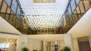A spacious lobby with a high ceiling, modern furniture, and a central decorative light installation. - City Comfort Inn Yuzhou Dayuxiang (Xuchang)