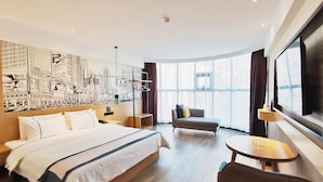 A hotel room with a large bed, a sofa, a small table, and a large window. - City Comfort Inn Yuzhou Dayuxiang (Xuchang)