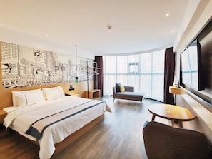 Hotellihuone, jossa on suuri sänky, sohva, pieni pöytä ja suuri ikkuna.
