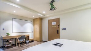 Une chambre d’hôtel comprenant un lit, un bureau avec une chaise, une armoire et une porte avec une pancarte.