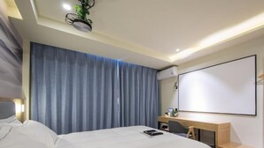 Une chambre d’hôtel moderne équipée d’un lit, d’un bureau et d’un grand miroir.
