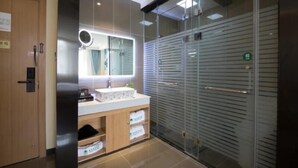 Une salle de bain moderne avec une douche à parois de verre, un lavabo avec un miroir et un meuble en bois contenant des serviettes.