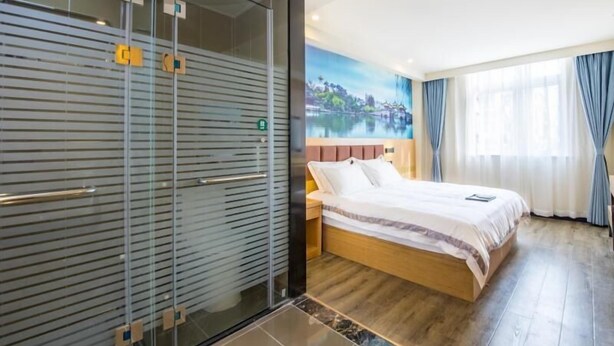 A hotel room with a bed, a nightstand, a glass partition, and a mural of a landscape. - Shell Yangzhou Jiangyang Middle Road Lotus Pool Hotel (Yangzhou)