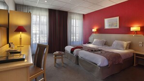 A hotel room with a bed, bedside tables, a desk, and a chair.