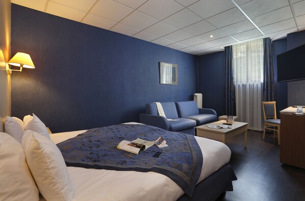 Une chambre d’hôtel avec un grand lit, un canapé, un bureau et une télévision.