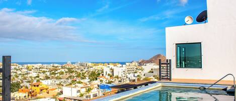 A rooftop pool with a view of a coastal cityscape.