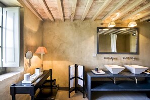 Un baño con dos lavamanos, un espejo, una lámpara y una ventana.