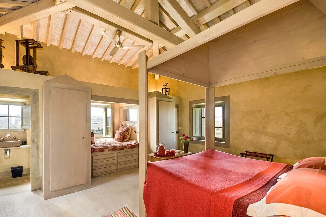 A bedroom with a large bed, a wardrobe, a mirror, and a window.