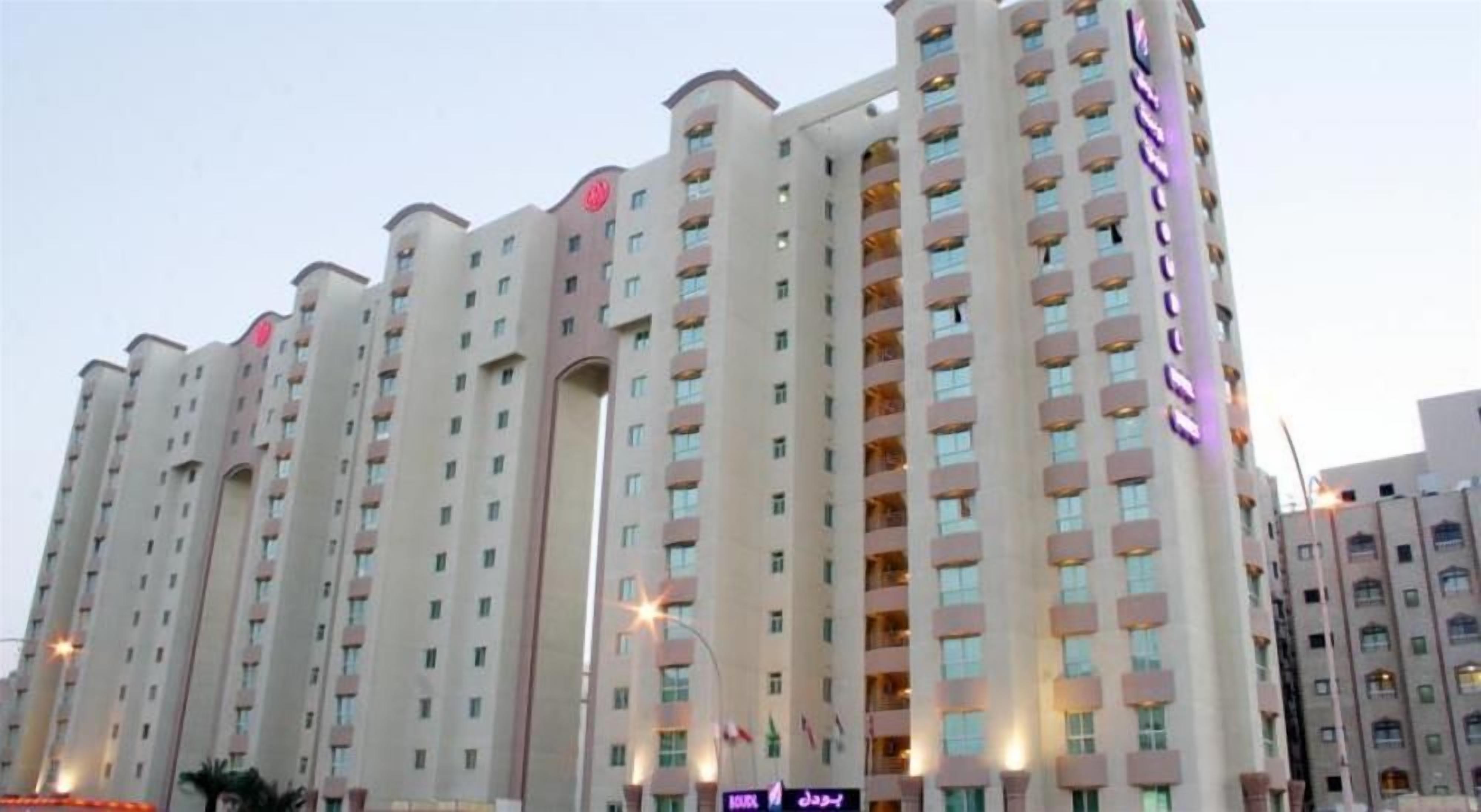 A multi-story hotel with a uniform facade, multiple balconies, and a prominent signage on the side.