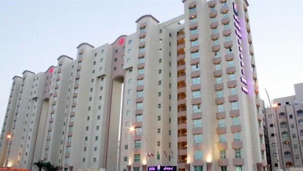 Un hotel de varios pisos con fachada uniforme, múltiples balcones y una señalización destacada en el lateral.