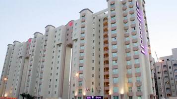 A multi-story hotel building with a modern architectural design, featuring balconies on each floor and a prominent signage on the facade.