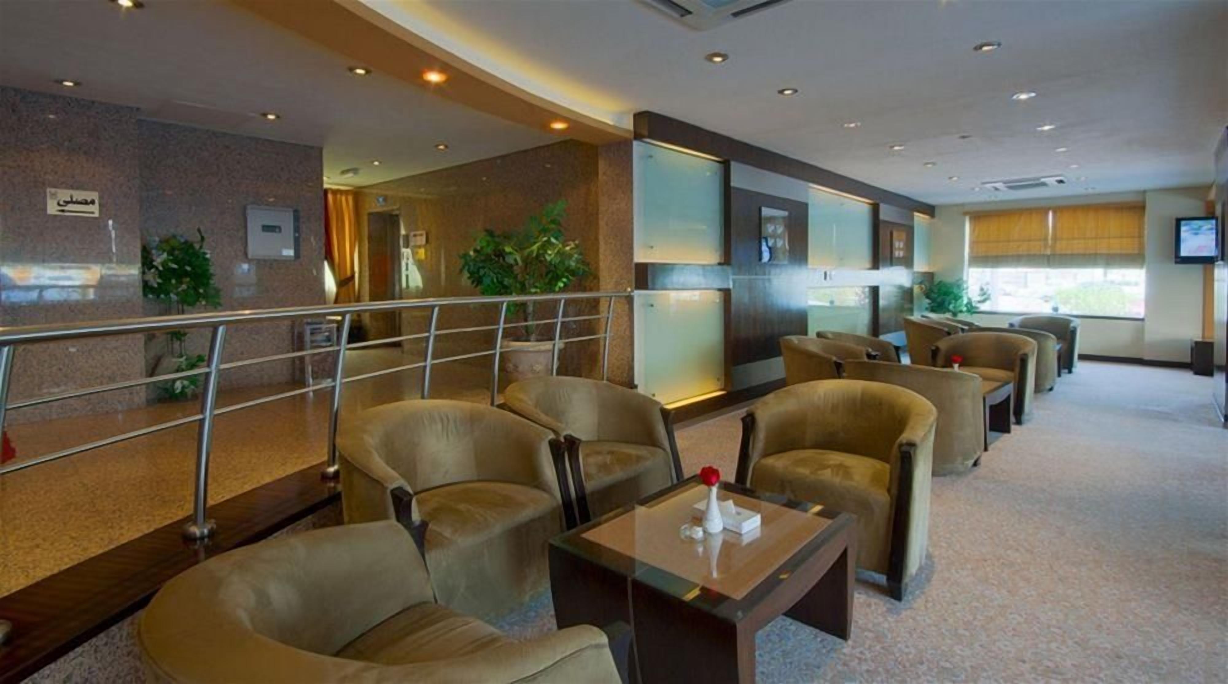 A hotel lobby with seating areas, a reception desk, and a large window.