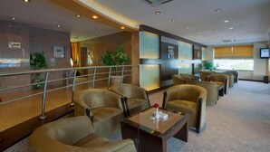 Un hall de hotel con zonas de estar, una escalera y un mostrador de recepción.