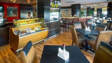 A hotel lobby with a reception desk, a dessert display, and seating areas.