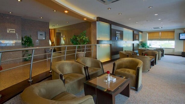 Eine Hotelhalle mit Sitzbereichen, einer Treppe und einer Rezeption.