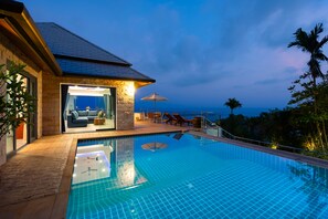 A swimming pool with a view of the ocean, a covered seating area, and a stone building with a glass door. - Tropical Villa a new stunning sea view Villa (Koh Samui)