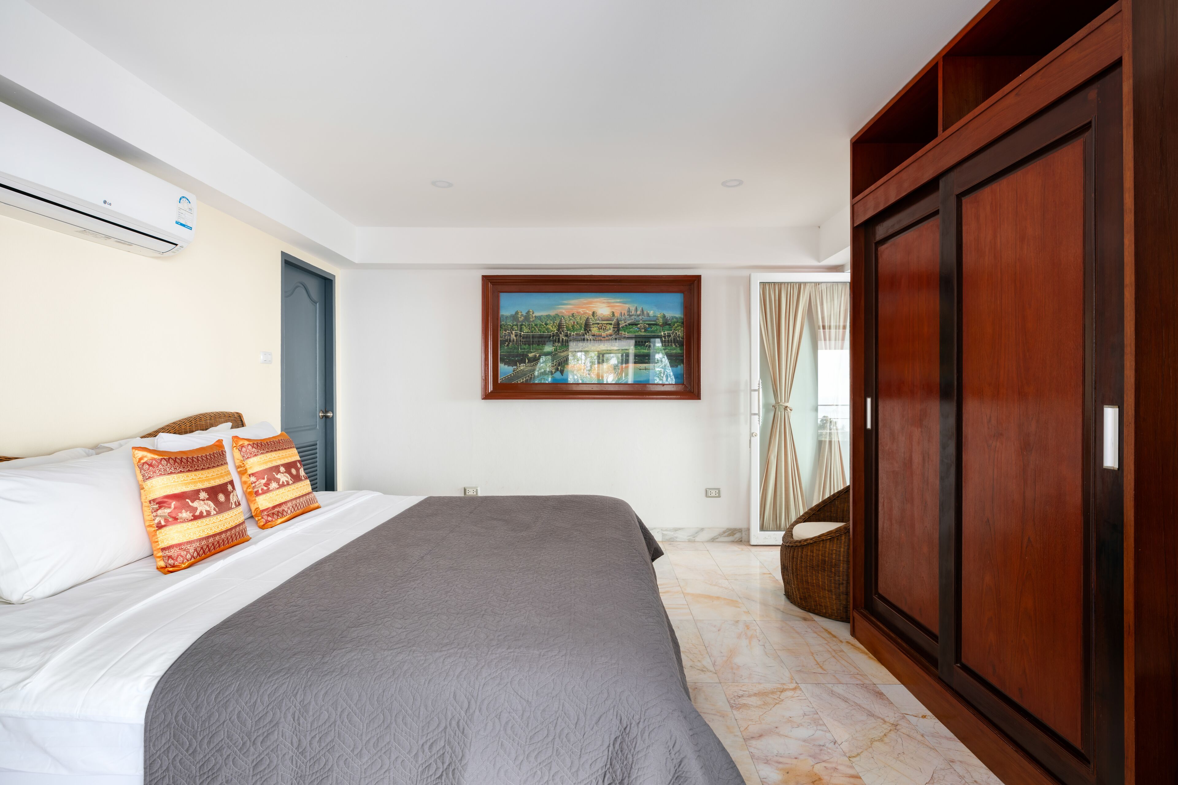 Ein Hotelzimmer mit Bett, großem Kleiderschrank, einem Bild an der Wand und Blick auf ein Gebäude durch das Fenster.
