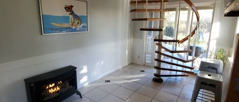 A spacious room with a fireplace, a spiral staircase, and a painting of a dog surfing.