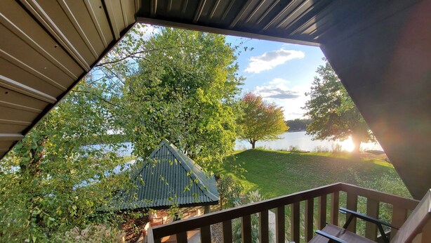 A covered outdoor area with a view of a lake, a gazebo, and a chair. - Tip of the Peninsula Lake House Retreat (South Bend)
