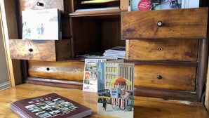 Ein Holztisch mit offenen Schubladen, ein Buch mit dem Titel 'Röbert' und Postkarten.