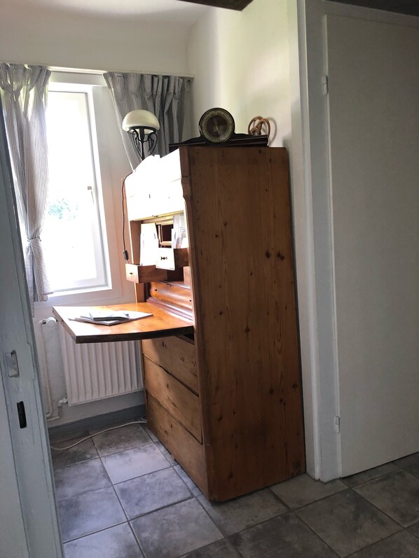 Une cuisine de taille réduite, dotée d’un plan de travail en bois, d’une petite fenêtre avec des rideaux et d’un radiateur.