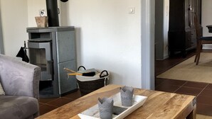 Ein Wohnzimmer mit Couchtisch aus Holz, grauer Couch und Kamin mit Schornstein.