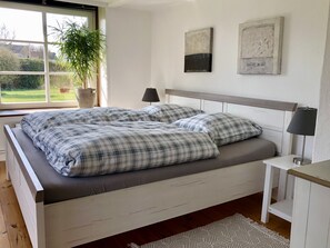 Een slaapkamer met een bed, nachtkastjes, een raam en uitzicht op de omgeving.