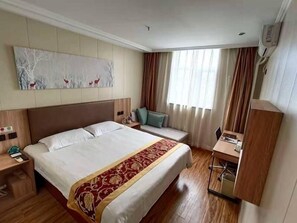 Une chambre d’hôtel avec un grand lit, une table de chevet, un bureau avec une chaise, une fenêtre avec des rideaux et un climatiseur fixé au mur.
