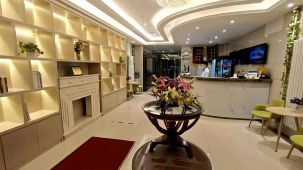 Un hall d’hôtel moderne avec une cheminée, un comptoir d’accueil et un grand lustre.