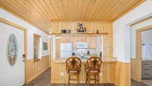 A kitchen with wooden cabinets, a white refrigerator, and a microwave. There are two wooden chairs at the counter. - Cabin 3, Aspen Leaf Lodges, Near Grand Lake (Grand Lake)