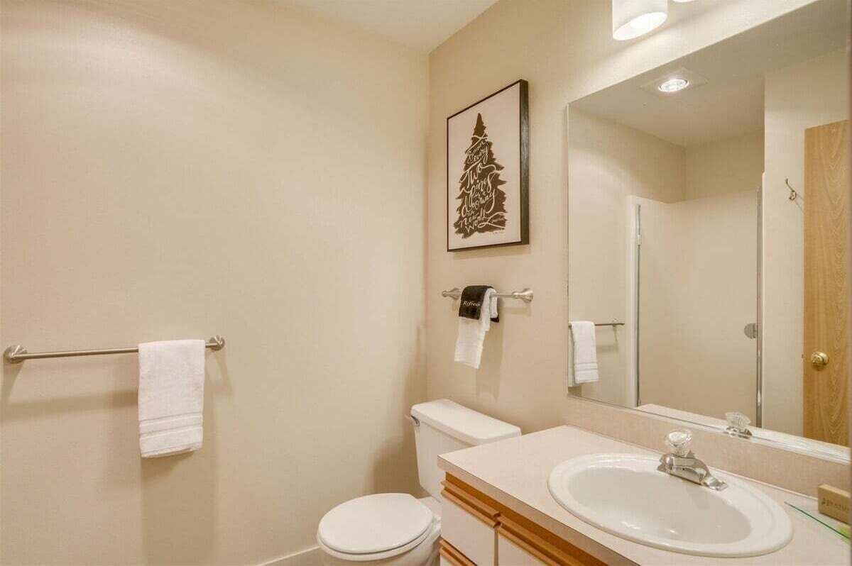 Ein Badezimmer mit Toilette, Waschbecken, Spiegel, Handtuchhalter und einem gerahmten Bild an der Wand.