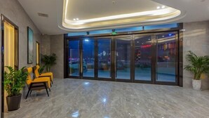A modern lobby with a marble floor, yellow seating, and large glass doors leading outside. - Greentree Inn Zhejiang Jiaxing Honghe Town Business Hotel (Jiaxing)