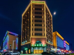 Un hôtel avec une enseigne bien visible, écrite dans une langue étrangère, comportant plusieurs étages et disposant d’un parking rempli de voitures.
