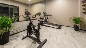 A modern gym with exercise equipment, a mirrored wall, and potted plants. - Greentree Inn Zhejiang Jiaxing Honghe Town Business Hotel (Jiaxing)