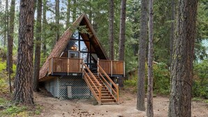 A cabin with a triangular roof, wooden deck, and a staircase leading to the entrance. - Pet-friendly A-Frame Near Plain & Leavenworth (Leavenworth)