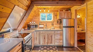 A compact kitchen with wooden cabinetry, a stainless steel refrigerator, and a window providing natural light. - Pet-friendly A-Frame Near Plain & Leavenworth (Leavenworth)