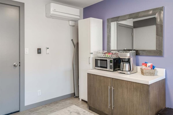 Een kitchenette met een magnetron, koffiezetapparaat en een bergkast.