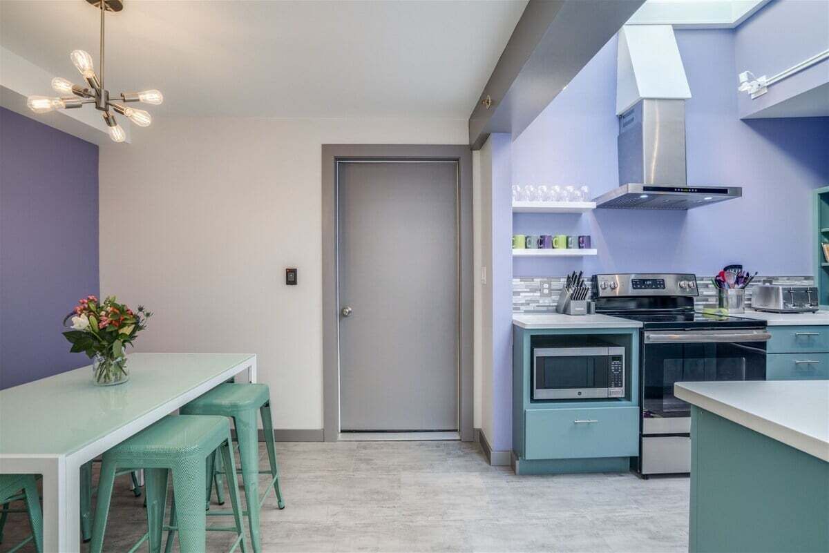 Una cocina compacta con comedor, microondas, horno y extractor de acero inoxidable.