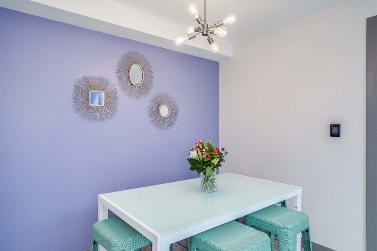 A dining area with a white table, green chairs, and a vase of flowers.