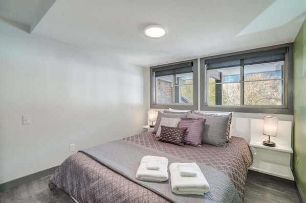 A bedroom with a bed, two bedside lamps, a window, and a ceiling light.