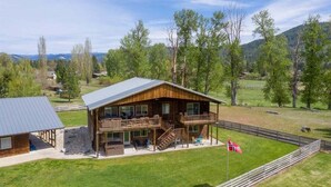 Eine Holzhütte mit Balkon, einem eingezäunten Garten und einer Flagge.